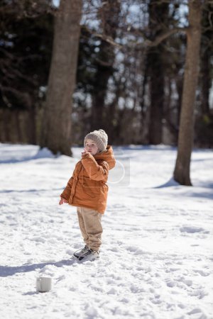 Portrait of two year old boy standing in fresh snow in winter playing outdoors