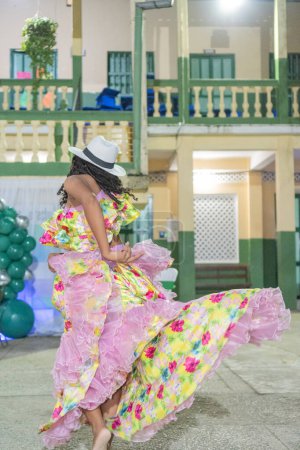 Foto de Bailarina femenina de cumbia atrapada en un remolino, su vestido floral fluyendo, complementado por un elegante sombrero de Panamá. - Imagen libre de derechos