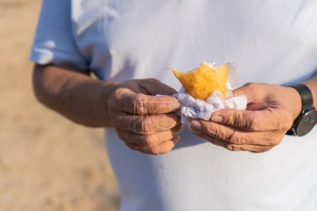 Detail shot of a senior man holding a half-eaten empanada.