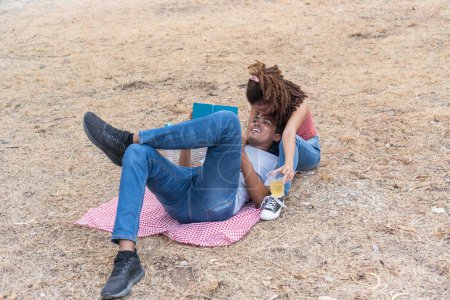 La mujer se inclina sobre el hombre en una pose juguetona en un picnic.