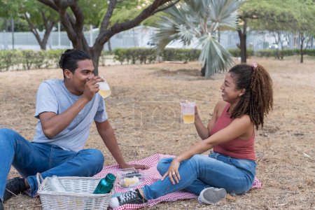 Couple sharing a laugh over drinks at a picnic.