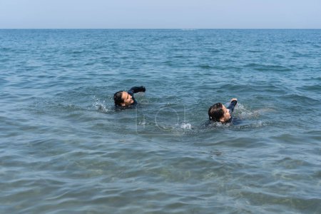 Two individuals swimming in calm ocean waters.