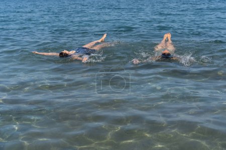 Zwei Schwimmer üben Rückwärtsschwimmen im kristallklaren Meerwasser.