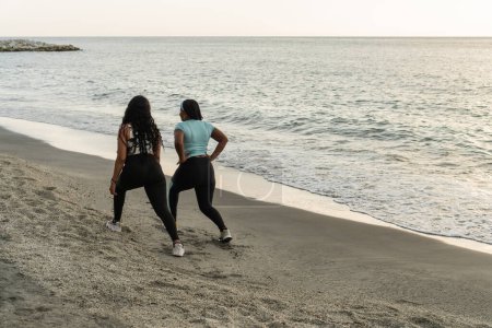 wo fitness enthusiasts enjoy an evening workout on the sandy shore.