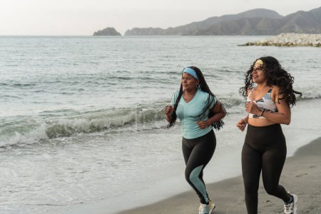 Women in workout attire jog together along the beach, enjoying the coastal scenery.