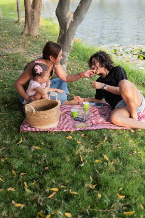 Family members laugh and share snacks during a cozy picnic by a lakeside, creating lasting memories.