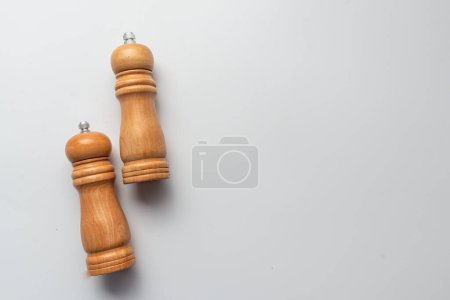 Photo for Salt and pepper wooden shakers, grinders on a white table with white background. - Royalty Free Image
