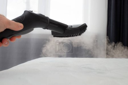 Téléchargez les photos : Nettoyer un matelas avec un nettoyant à vapeur. - en image libre de droit