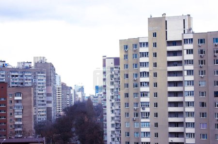 Foto de Kiev, Ucrania - 2 de enero de 2022: Fotografía de cambio de inclinación de edificios de apartamentos en la comunidad dormitorio, área de la ciudad de cercanías. Vista desde una ventana en una calle, techos. Complejo de apartamentos en la gran ciudad durante el día. - Imagen libre de derechos