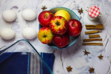 Zutaten für die Zubereitung eines traditionellen amerikanischen Apfelkuchens zu Hause zu Thanksgiving. Rote reife Äpfel, Hühnereier, Anis-Gewürze, Zimtstangen auf einem blauen Küchentuch flach auf einem Tisch. Herbstsaison.