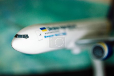 Photo for Kyiv, Ukraine. 1 May 2022 A nose of a white toy airplane of the Ukraine International company, airliner on a blue background. Aircraft transportation for traveling trips, airpots. Model plane details. - Royalty Free Image