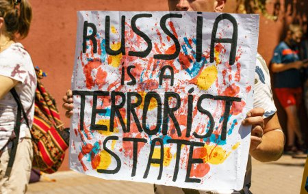 Photo for Madrid, Spain July 1, 2022 People at a rally in support of Ukraine in connection with Russias war against Ukraine. A man holding a banner with the text Russia is a terrorist state Stop Putin - Royalty Free Image