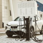Kyiv, Ukraine February 2, 2023 A white electric car is charged with electricity at a power station. Ecological transport at the electric filling station in winter A parking lot for cars in city street