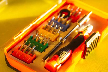 Ein Satz verschiedener Schraubendreher-Bits mit unterschiedlichen Befestigungen in einer orangefarbenen Plastikbox. Verschiedene Schraubenzieher für Reparaturarbeiten. Werkzeugset für kleine Reparaturen. Schraubenzieher-Tip-Set.