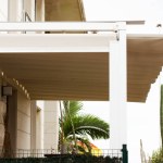Attached pergola on a villa in Spain. A modern or classic hotel on the tropical resort. White wooden long courtyard canopy over house entrance, cottage. Front door canopies. 