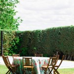 Beautifully set tables with floral tablecloths. Private backyard party. Comunion in Spain, traditional catholic holidaycelebration, fiesta in nature. Garden furniture, round wooden tables and chairs. 