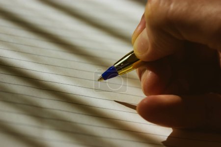 Photo for A ballpoint pen in a woman's hand. A man writes in a blank notebook. Life from a clean slate, planning, goal building, business strategy concept. Writing school. A writer composes a poem, an essay. - Royalty Free Image