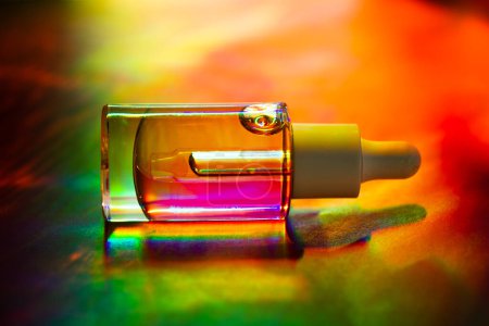 Glass cosmetic pipette bottle on multicolor background. Decorative cosmetics. Facial serum. Fashion magazine style photo. 