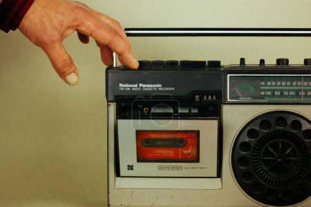 Photo for Madrid, Spain. May 2, 2023 A man put music cassette into an old record player. Nostalgia for '90s. Vintage tape recorder Ghetto blaster Music boom box - Royalty Free Image