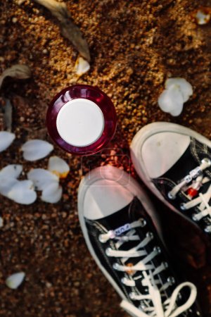 Foto de Madrid, España. enero 7, 2024 Negro vintage Converse zapatillas de deporte, pies de mujer, botella de color rosa con vista al agua. Zapatos vintage. Nostalgia de los 90. - Imagen libre de derechos