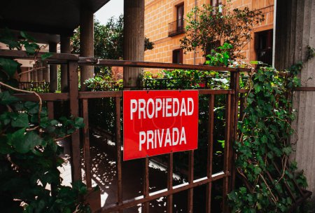 Téléchargez les photos : Madrid, Espagne. 1 mai 2023 Un panneau d'avertissement, plaque rouge avec un texte 'Propriété privée' en espagnol 'Propiedad privada'. Portail fermé, entrée d'une maison. - en image libre de droit