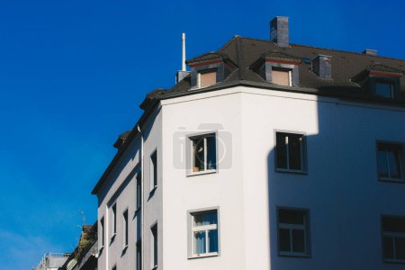 Interior de casa residencial, fragmento de una fachada blanca de una mansión con ventanas y techo gris contra un cielo azul. Arquitectura del centro histórico. 