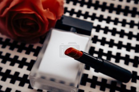 Bottle perfumed water, red lipstick on black white background, blooming fragrant tea rose on table top view. Female beauty concept. Women's lifestyle.