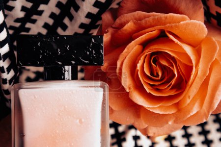 Eine Flasche parfümiertes Wasser, roter Lippenstift auf schwarz-weißem Hintergrund, blühende duftende Teerose auf der Tischplatte. Weibliches Schönheitskonzept. Lebensstil von Frauen.