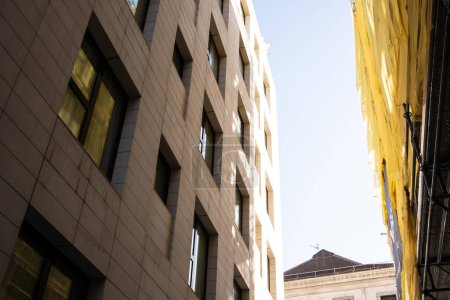 Vue en angle bas d'une façade de bâtiment recouverte d'un filet de protection en filet jaune. Site de construction. Rénovation appartement. Scène urbaine