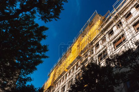 Yellow scaffolding construction on a building facade. Thermal insulation of a house. Multistory apartment buildings. Real estate construction works.
