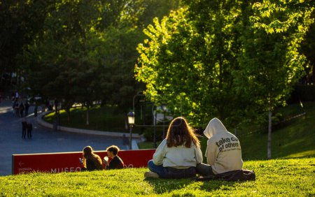 Foto de Madrid, España. Mayo 1, 2024 Los residentes de la ciudad se relajan sentados en la hierba verde del césped en el día soleado de primavera. Gente en la naturaleza cerca del Museo del Prado. - Imagen libre de derechos