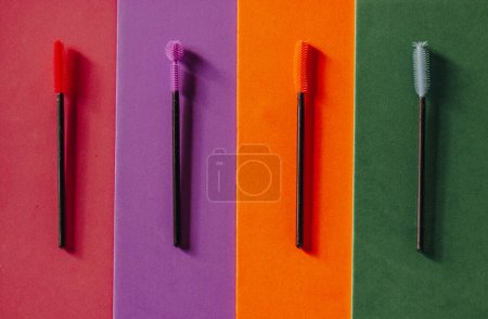 Conjunto de pinceles de rímel de silicona multicolor sobre un fondo brillante multicolor. Cepillos de pestañas verdes, rosados, morados y anaranjados. Cosmética decorativa moderna para mujer. Belleza femenina y moda glamurosa. 
