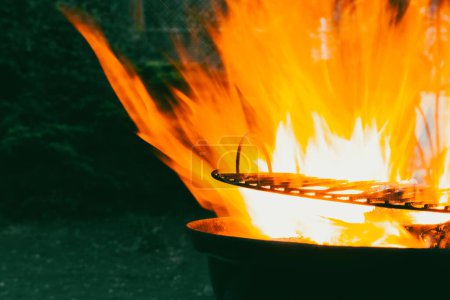 Feuerflammen auf dunklem Hintergrund. Schöne brennende Holzkohle in windiger Nacht. Kochen in der Natur. Vorbereitung im Freien. Flamme auf schwarzem Hintergrund. 