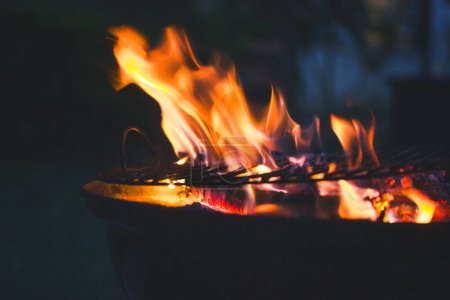 Feuerflammen auf dunklem Hintergrund. Schöne brennende Holzkohle in windiger Nacht. Kochen in der Natur. Vorbereitung im Freien. Flamme auf schwarzem Hintergrund. 