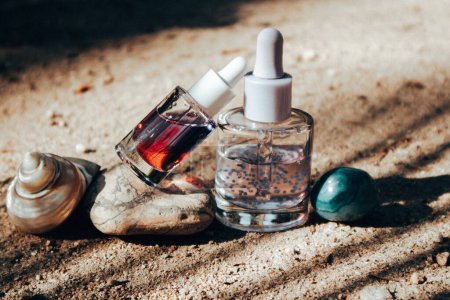 Anti-Aging-Serum-Pipettenflaschen auf einem Steinpodest. Dekorative Kosmetik auf beigem Sandgrund mit Palmen-Schatten. Weibliche Hautpflege.