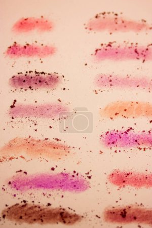 Fond vertical de frottis dessinés avec une variété d'ombres à paupières roses et orange. Cosmétiques décoratifs pour femmes. Cosmétique barbouillé. Outils de beauté féminine