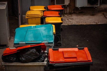 Bunte, helle Müllcontainer zum Sortieren diverser Abfälle in einem Hinterhof. Mülltonnen zur Trennung verschiedener Arten von Abfallstoffen. Mülleimer.