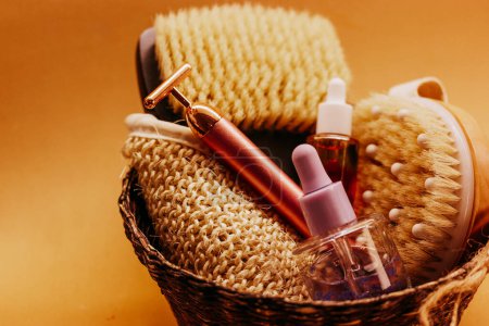 A basket of hard-bristled massage brushes, glass cosmetic jars with facial serum. Take care of your body, facial skin. Beauty products. Face massager.