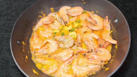 Fry shrimps in a pan with herbs and garlic. on dark background. View from above