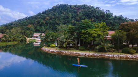 Photo for Women paddling at a sup board at a Klong lake in the rainforest in Koh Chang Thailand. stand-up paddleboard - Royalty Free Image