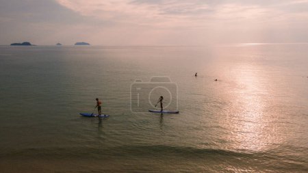 Photo for A couple of men and women paddling at a sup board in Koh Chang Thailand during sunset. stand-up paddleboard - Royalty Free Image