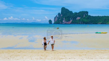 Foto de Un par de hombres y mujeres caminando por la playa bajo el sol de la mañana. Loh Dalum Beach Koh Phi Phi Tailandia - Imagen libre de derechos
