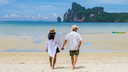 Téléchargez les photos : Koh Ph Phi Thaïlande, un couple d'hommes et de femmes marchant sur la plage au soleil du matin. Loh Dalum Beach Koh Phi Phi Thaïlande - en image libre de droit