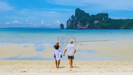 Foto de Un par de hombres y mujeres caminando por la playa bajo el sol de la mañana. Loh Dalum Beach Koh Phi Phi - Imagen libre de derechos