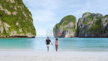 Foto de Las mujeres tailandesas y los hombres caucásicos caminan en la playa de Maya Bay Beach Koh Phi Phi Tailandia por la mañana con el océano de color turquesa. - Imagen libre de derechos