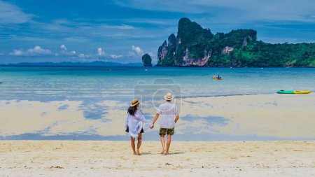 Foto de Koh Ph Phi Tailandia, un par de hombres y mujeres caminando por la playa bajo el sol de la mañana. Loh Dalum Beach Koh Phi Phi - Imagen libre de derechos