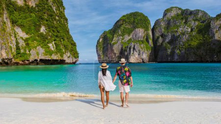 Foto de La parte trasera de las mujeres tailandesas y los hombres caucásicos con un paseo sombrero en la playa de Maya Bay, playa Koh Phi Phi Tailandia por la mañana con turqouse color océano. - Imagen libre de derechos