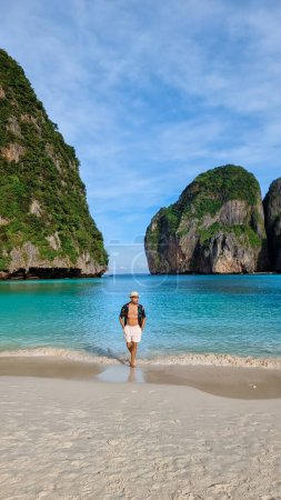 Téléchargez les photos : Jeunes hommes caucasiens avec short de bain et un chapeau sur la plage de Maya Bay Koh Phi Phi Thaïlande. - en image libre de droit