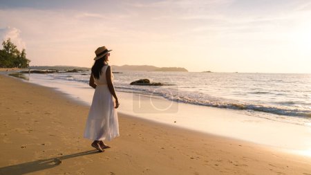 Photo for Thai women with a dress walk at the beach during sunset in Khao Lak Thailand. - Royalty Free Image