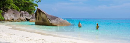 Téléchargez les photos : Un couple d'hommes et de femmes sur la plage de sable blanc tropical avec turqouse couleur océan des îles Similan Thaïlande. - en image libre de droit